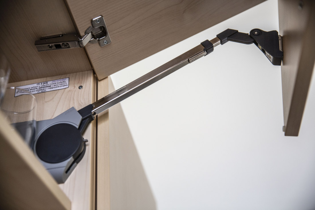 Detail výklopného mechanismu u skříňky školního nábytku umožňující tiché a plynulé dovírání dvířek