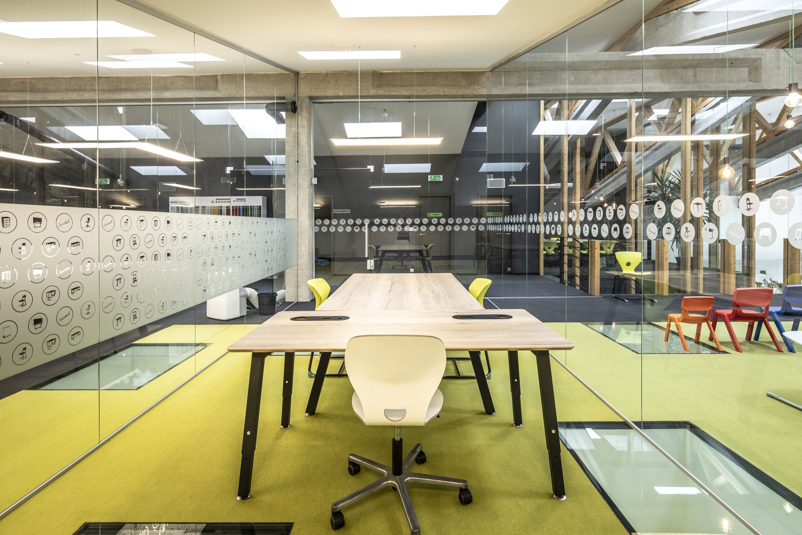 Jednací stůl v prosklené zasedací místnosti oddělené od kanceláře skleněnými příčkami