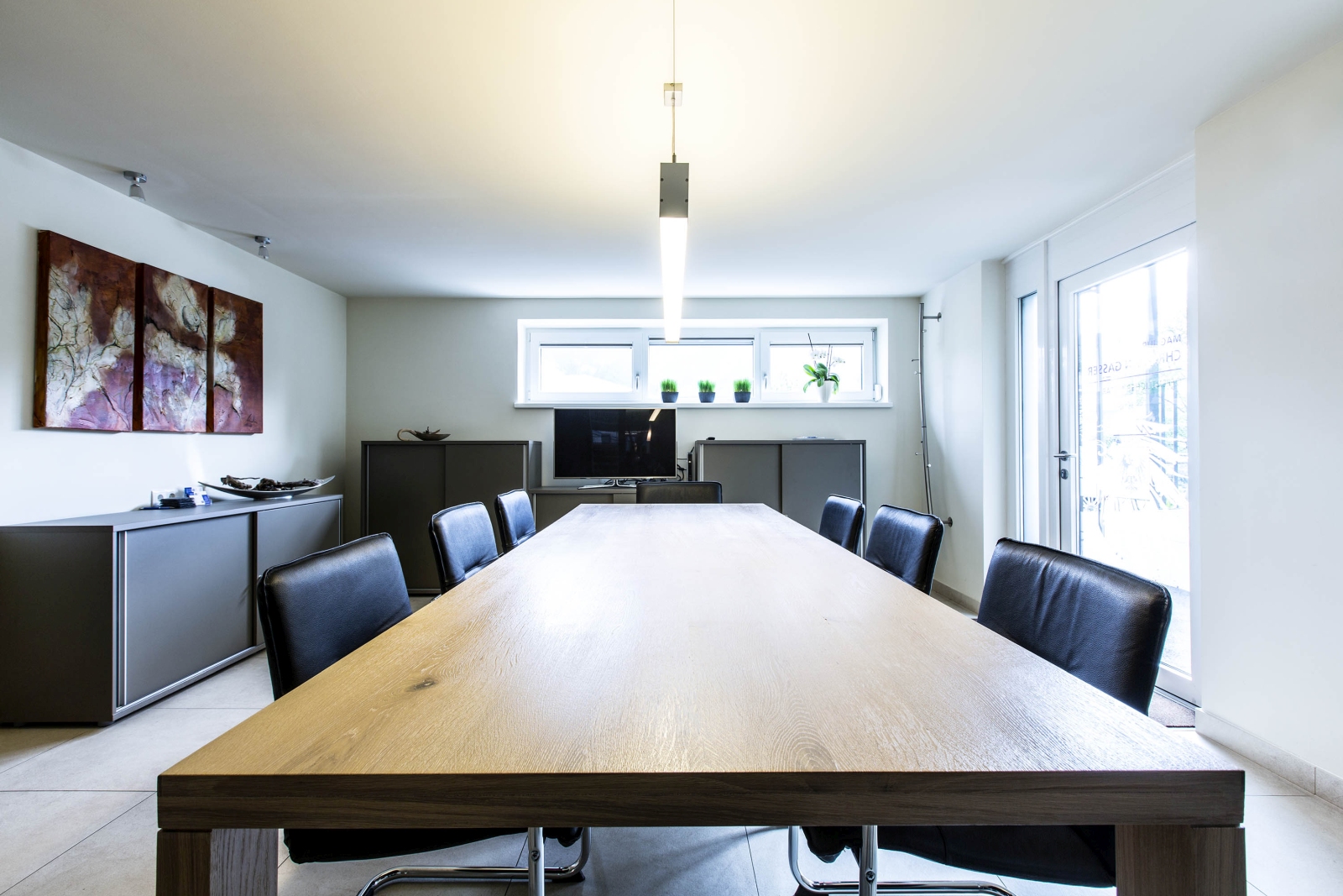 Velký dřevěný zasedací stůl v jednací místnosti se židlemi po obvodu