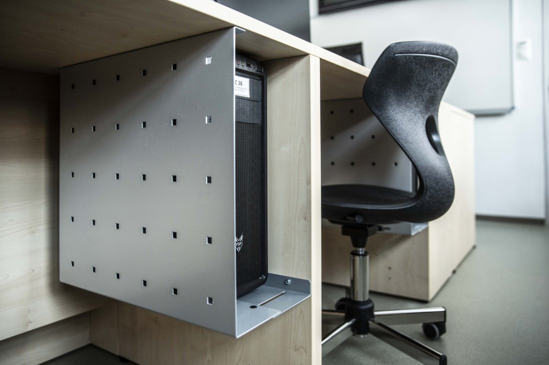 Počítač upevněný v kovovém držáku pod pracovní deskou stolu